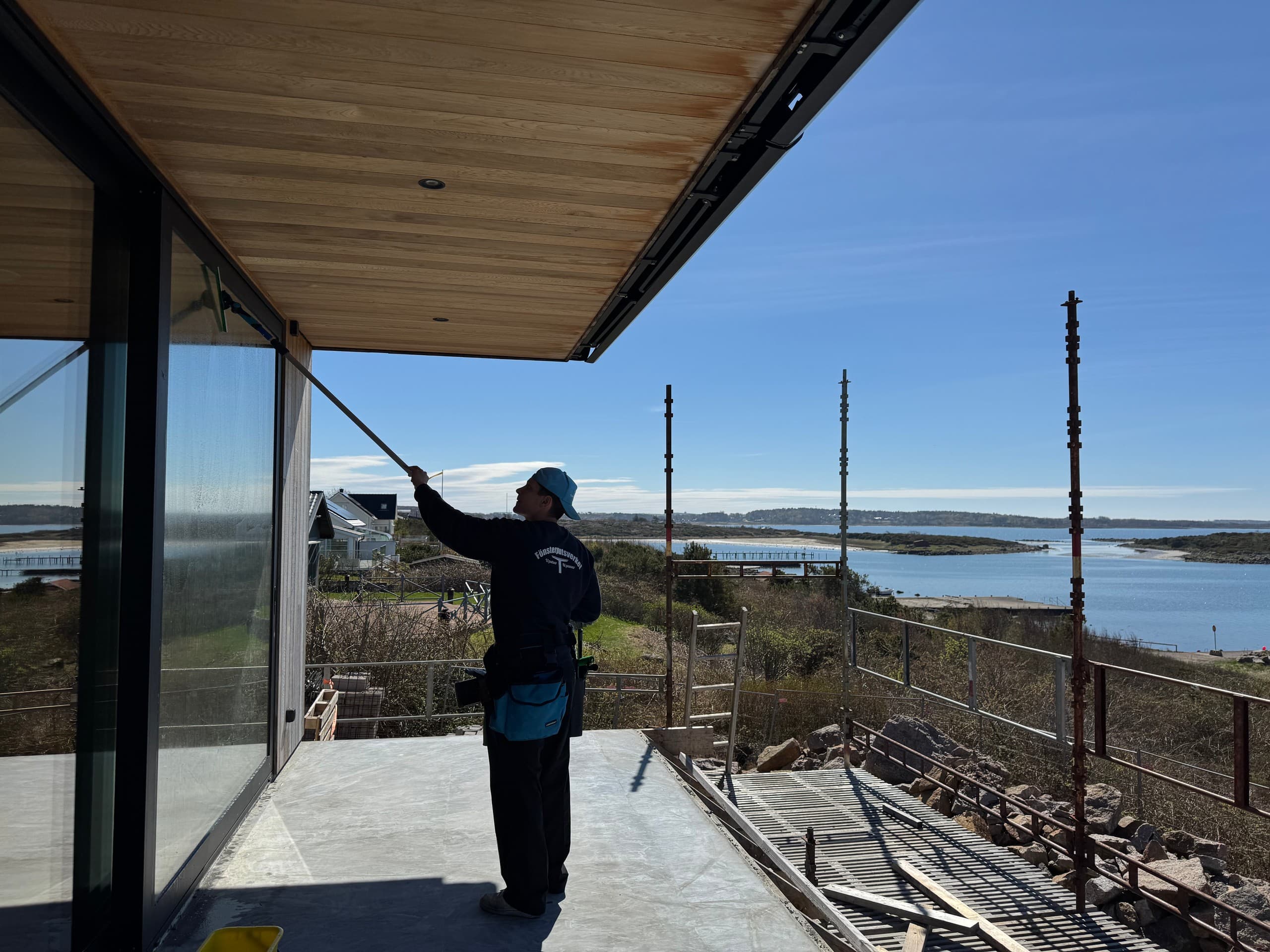 Fönsterputsare rengör glaspartier på ett hus vid havet